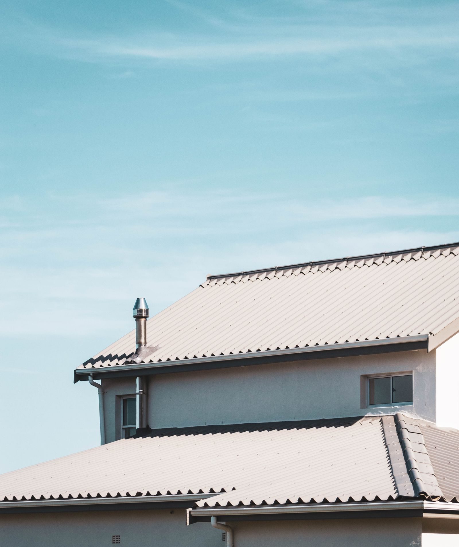 A clean white roofline with new guttering against a blue sky